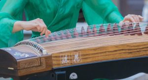 woman in green dress playing guzheng
