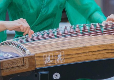 woman in green dress playing guzheng